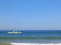 Almada, Portugal. August 22, 2023: Small traditional fishing boat sailing across the Fonte da Telha Beach in Costa da Caparica Royalty Free Stock Photo