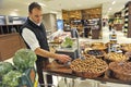 Almaty, Kazakhstan - 11.07.2012 : An employee of a large hypermarket puts vegetables in sections Royalty Free Stock Photo