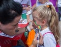 ALMATY, KAZAKHSTAN - JUNE 10, 2018: Unidentified girl makeup artist makes a bright carnival face painting to the