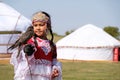 Almaty / Kazakhstan - 09.23.2020 : A little girl in Kazakh national dress holds a Balaban Falcon in her arms