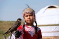 Almaty / Kazakhstan - 09.23.2020 : A little girl in Kazakh national dress holds a Balaban Falcon in her arms