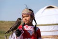 Almaty / Kazakhstan - 09.23.2020 : A little girl in Kazakh national dress holds a Balaban Falcon in her arms