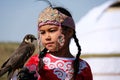 Almaty / Kazakhstan - 09.23.2020 : A little girl in Kazakh national dress holds a Balaban Falcon in her arms