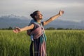 Young beautiful babywearing mother carry her newborn baby in a ring sling in rural field scene