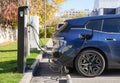 Almaty, Kazakhstan - November 11, 2023: The charger plug is inserted into a BMW iX xDrive40 in a parking lot