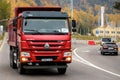 Red Chinese dump truck CNHTC Howo Sinotruk driving down the Almaty street