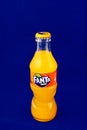 Almeria, Spain; November 25th, 2021: 200ml Orange flavoured Fanta bottle, Classic glass bottle with metal cap isolated on blue. Royalty Free Stock Photo