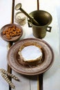 Almond Camembert or brie cheese circle in brown kraft paper decorated, on an earthenware plate, spice dish on a light wooden backg Royalty Free Stock Photo