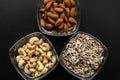 Almond, cashew and sunflower seeds in a small plates which standing on a black table. Nuts is a healthy vegetarian