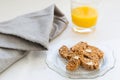 Almond and chocolate biscotti in vintage scalloped glass plate, with grey serviette and small glass of orange juice