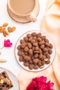 Almond in chocolate dragees on ceramic plate and a cup of coffee on white concrete background. Top view, close up Royalty Free Stock Photo