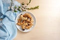 Almond crescent cookies on a plate, spring flower branch and blue napkin on a light wooden table, large copy space, high angle