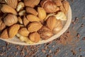 Almond and hazelnuts in a wooden spoon on a dark background