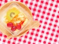 Almond jelly Tao Huay Fruit Salad topped various fruit on circle wooden tray over red checkered napkin and spoon. Royalty Free Stock Photo