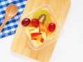 Almond jelly Tao Huay Fruit Salad topping mix fruit on chopping board and spoon, blue checkered napkin over white background. Royalty Free Stock Photo