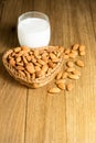 Almond milk in glass with almonds in basket heart shape