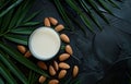 Almond milk in glass and almonds with green leaves on black background Royalty Free Stock Photo