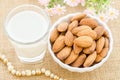 Almond milk in glass and almonds in white cup.