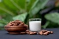 Almond milk in a glass with almonds in wooden bowl on black table