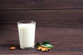 Almond milk in a glass on a wooden background. scattered almonds and green leaves next to the glass. space for text Royalty Free Stock Photo