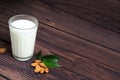 Almond milk in a glass on a wooden background. scattered almonds and green leaves next to the glass. space for text Royalty Free Stock Photo