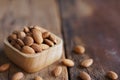 Almond nut in wood bowl on wooden table with green leaf background Royalty Free Stock Photo