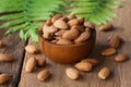 Almond nut in wood bowl on wooden table with green leaf background Royalty Free Stock Photo