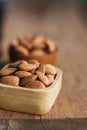 Almond nut in wood bowl on wooden table with green leaf background Royalty Free Stock Photo