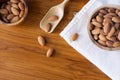 Almond nut in wood bowl on wooden table with green leaf background Royalty Free Stock Photo