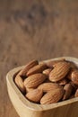 Almond nut in wood bowl on wooden table with green leaf background Royalty Free Stock Photo