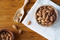 Almond nut in wood bowl on wooden table with green leaf background Royalty Free Stock Photo