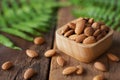 Almond nut in wood bowl on wooden table with green leaf decoration background Royalty Free Stock Photo