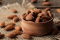 Almond nut in a wooden bowl close-up on a napkin on a brown wooden table