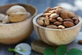 Almond nut in wooden bowl on wood table with green leaf background, copy space Royalty Free Stock Photo