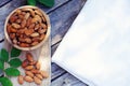 Almond nut in wooden bowl on wood table with green leaf background, copy space Royalty Free Stock Photo