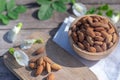 Almond nut in wooden bowl on wood table with green leaf background, copy space Royalty Free Stock Photo