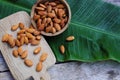 Almond nut on wooden cutting board on wood table with green leaf background, copy space Royalty Free Stock Photo