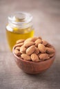 Almond nuts in wooden bowl and almond oil in bottle on wood textured background. Copy space. Superfood, vegan, vegetarian food