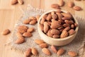 Almond seeds in a bowl wood on the sackcloth on table wooden background