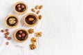 Almond walnut hazelnut chocolate small tarts on a white background, space for text