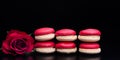 Red macaroon on black background with red roses