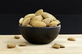Almonds in black porcelain bowl on wooden table with unfocused background Royalty Free Stock Photo