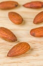 Almonds in brown bowl on textured wooden background.