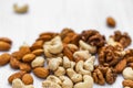 Almonds, cashews and walnuts scattered on a white wooden background