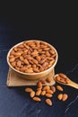 Almonds on dark stone table with wood spoon