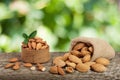 Almonds with leaf in bag from sacking on a wooden table with blurred garden background