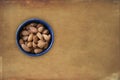 Almonds lying in a blue bowl with brown grunge background. Top view image with blank copy space for text