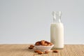 Almonds milk in a glass bottle and roasted almonds on brown wooden mat, copy space concept. Royalty Free Stock Photo