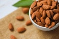 Almonds nuts on bowl with leaf top view on sack background - Roasted almond for snack