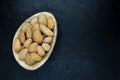 Almonds with the Nutshell in Eco Natural Banana Leaf Plate on Black Stone Background Surface with Free Space Royalty Free Stock Photo